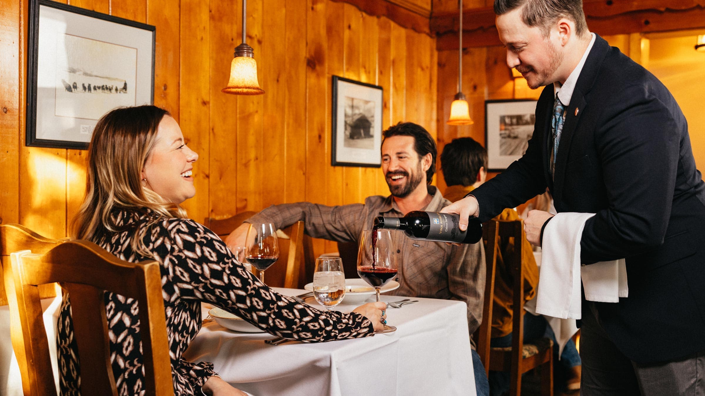 Waiter pouring wine for a couple having dinner.