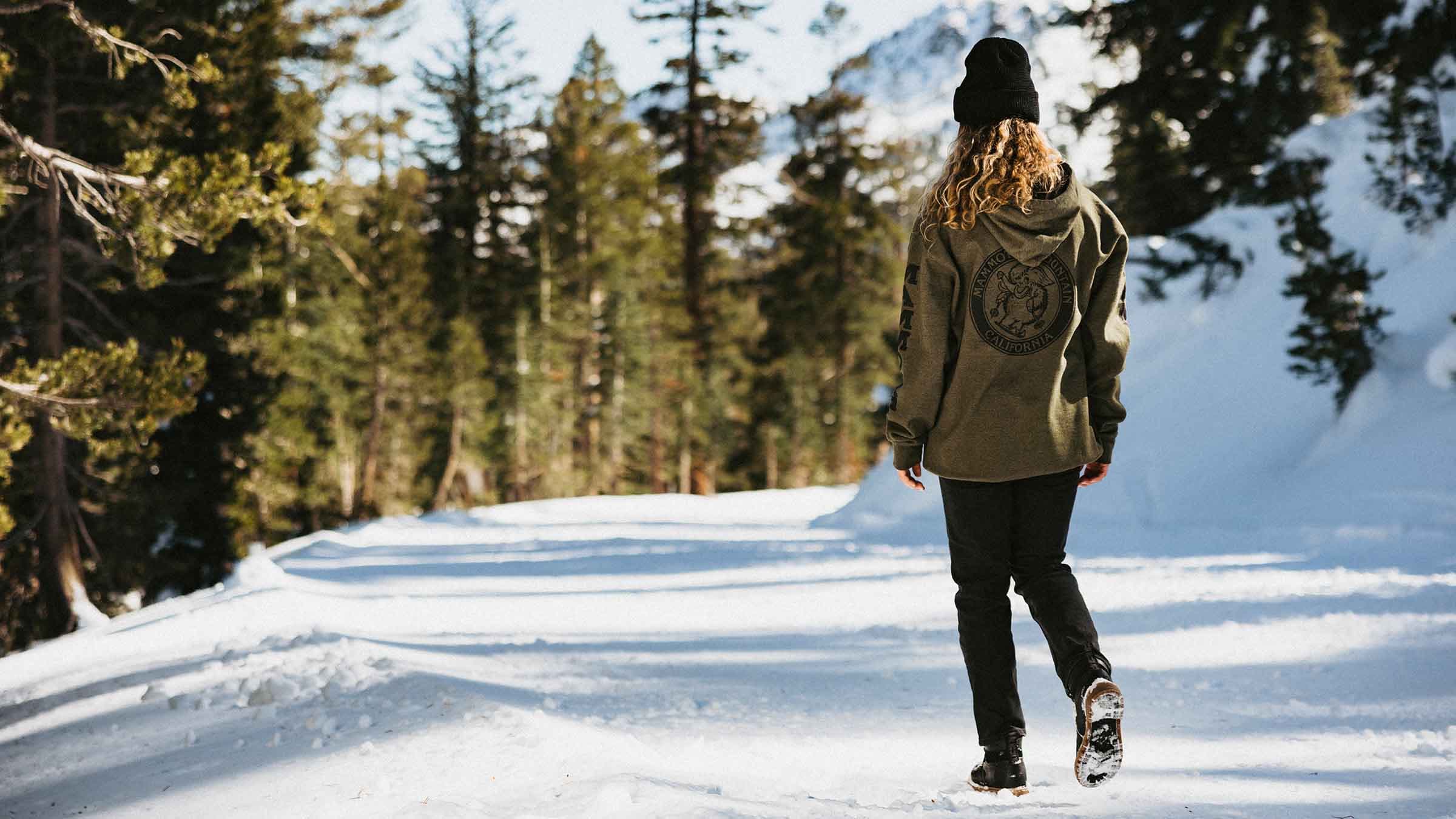 Girl walking through the snow with a Mammoth hoodie
