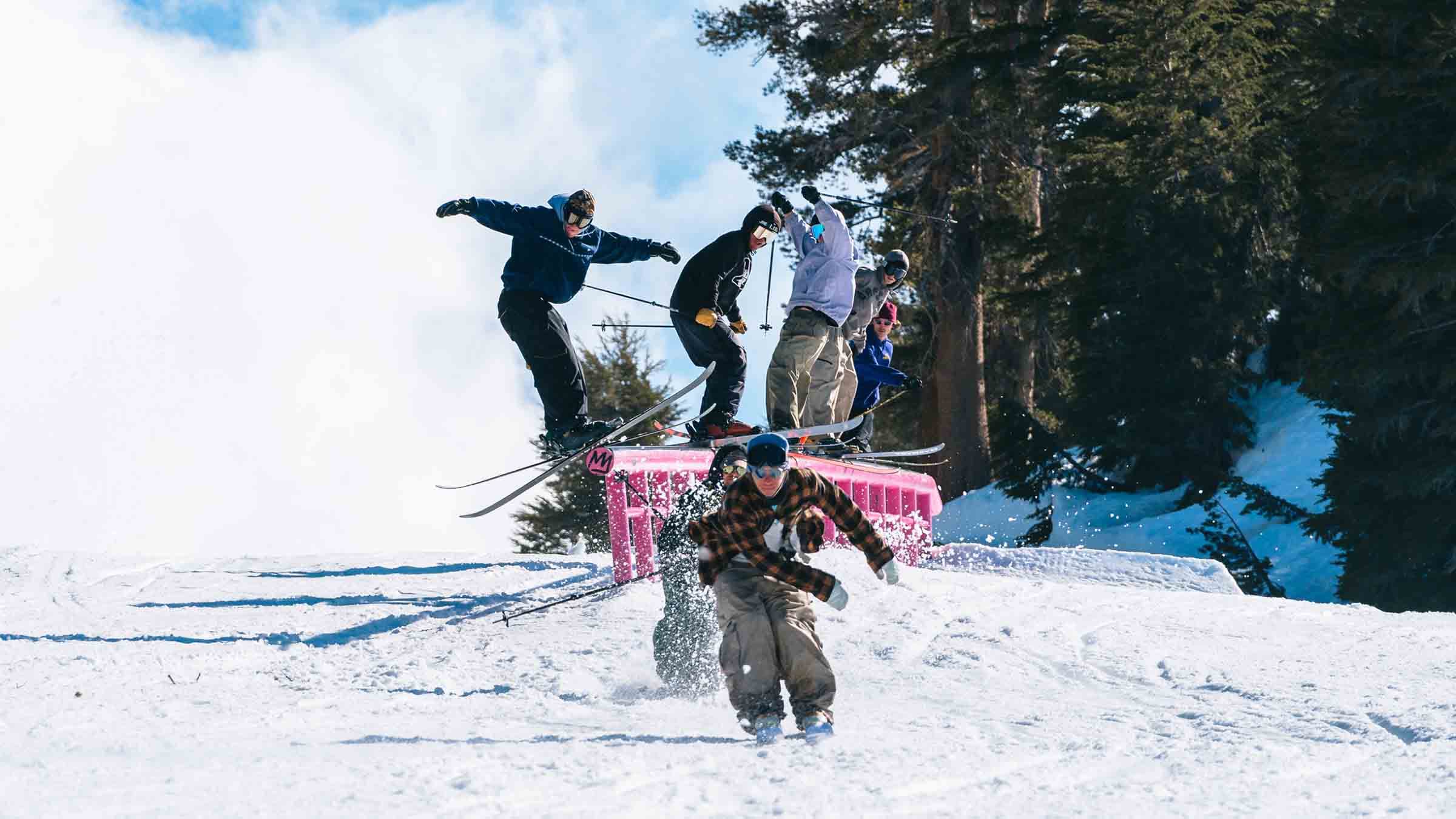 A group of skiers riding down a rail