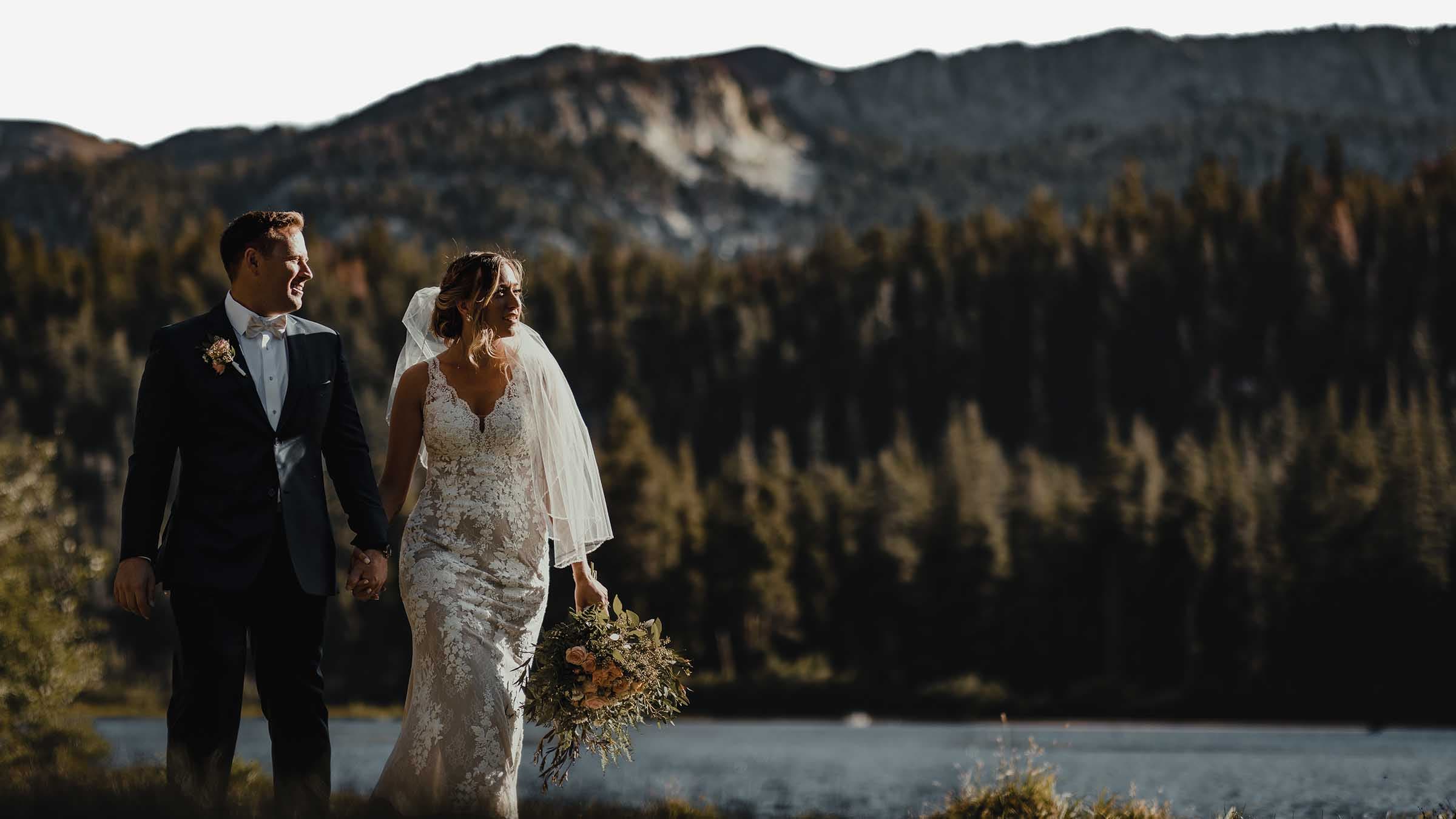 A couple hand in hand walking along a lake next to Forest Chapel wedding venue